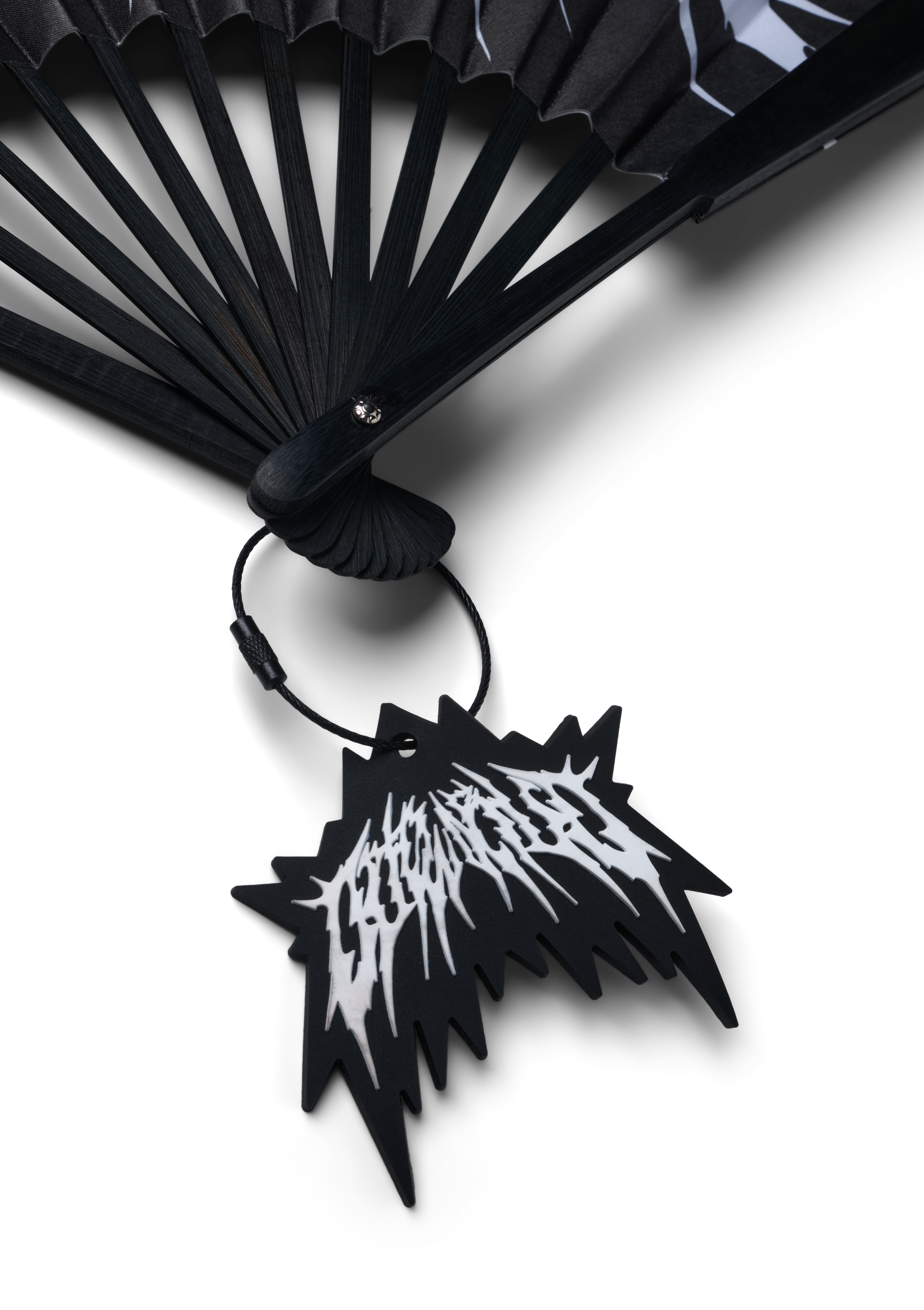 Nahaufnahme des unteren Drehpunkts des Fächers. Zu sehen ist der Verschlussmechanismus sowie der daran befestigte schwarze Tag mit gezackter Form und weißem OUTWORLD-Logo.